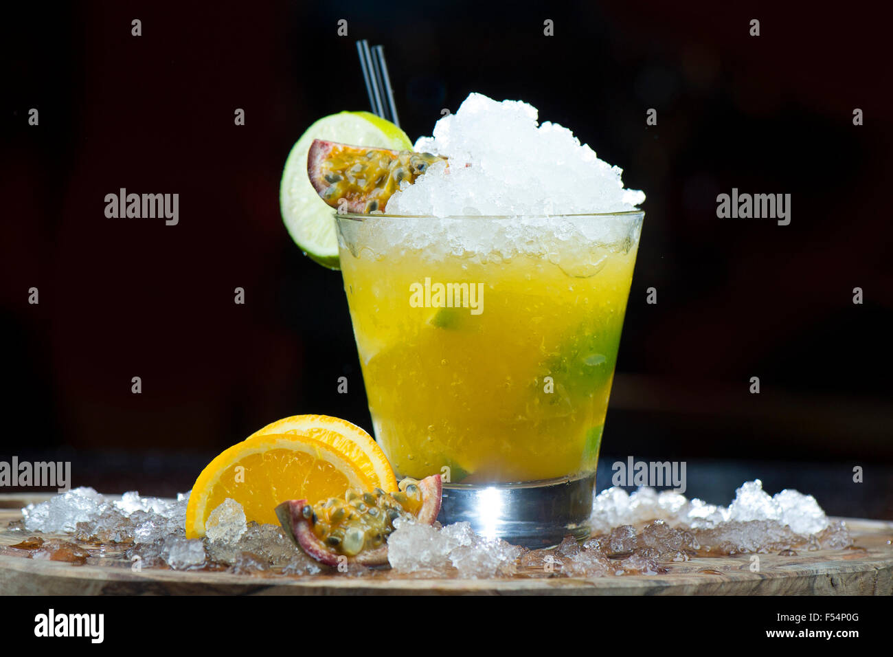 Un rinfrescante giallo passione cocktail di frutta con ghiaccio e fettine di arancia. Foto Stock