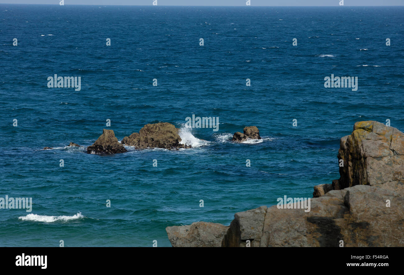Onde sbattere contro le rocce in luminoso blu del mare al largo della costa di St Ives in Cornovaglia Foto Stock
