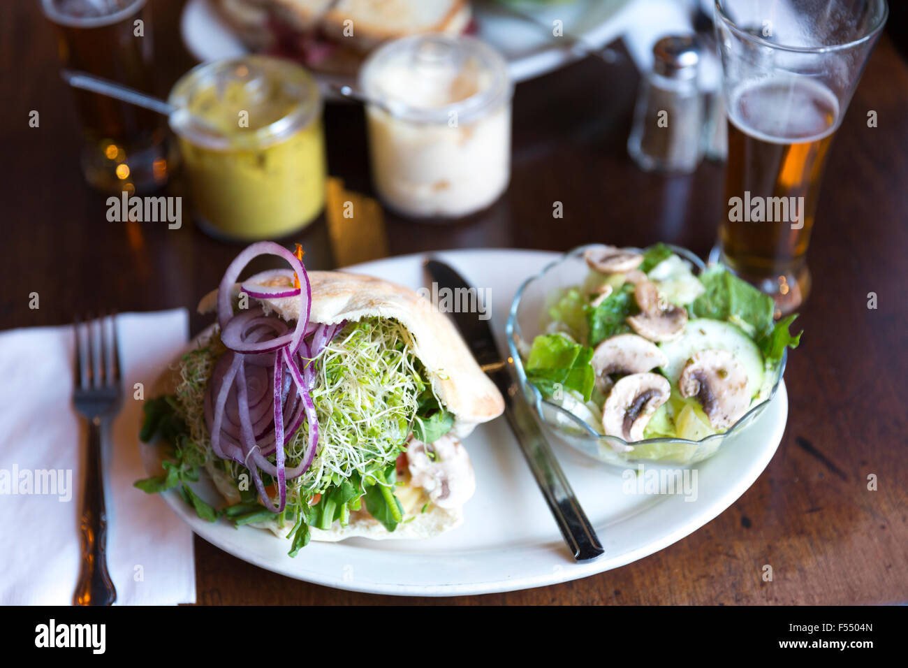 Giant deli sandwich di pane con cipolla, la senape e il crescione e insalata e birra presso il bar diner ristorante Soho di New York, Stati Uniti d'America Foto Stock