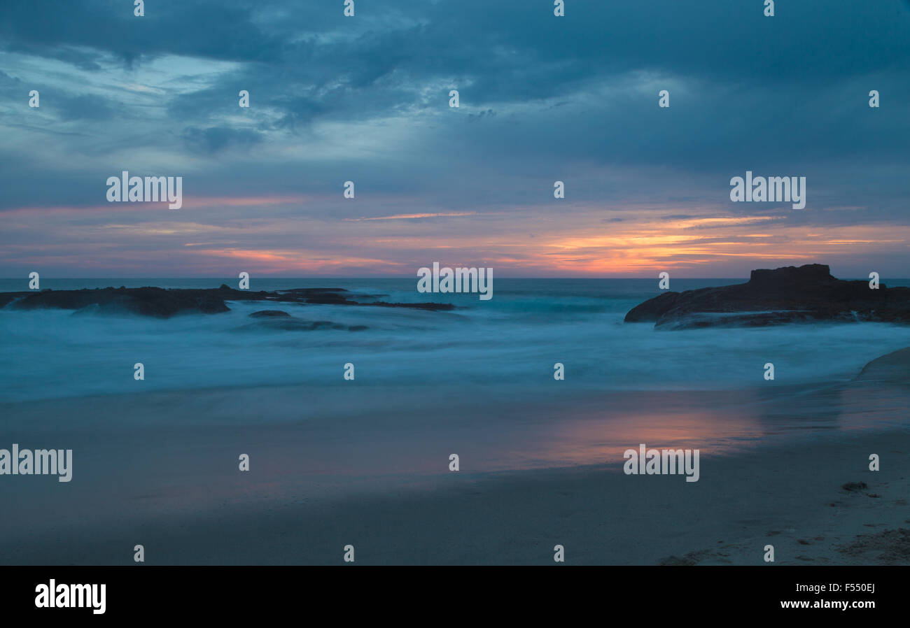 Una lunga esposizione di rocce in onde, dando una nebbia simile effetto sull'oceano in Laguna Beach in California al tramonto Foto Stock