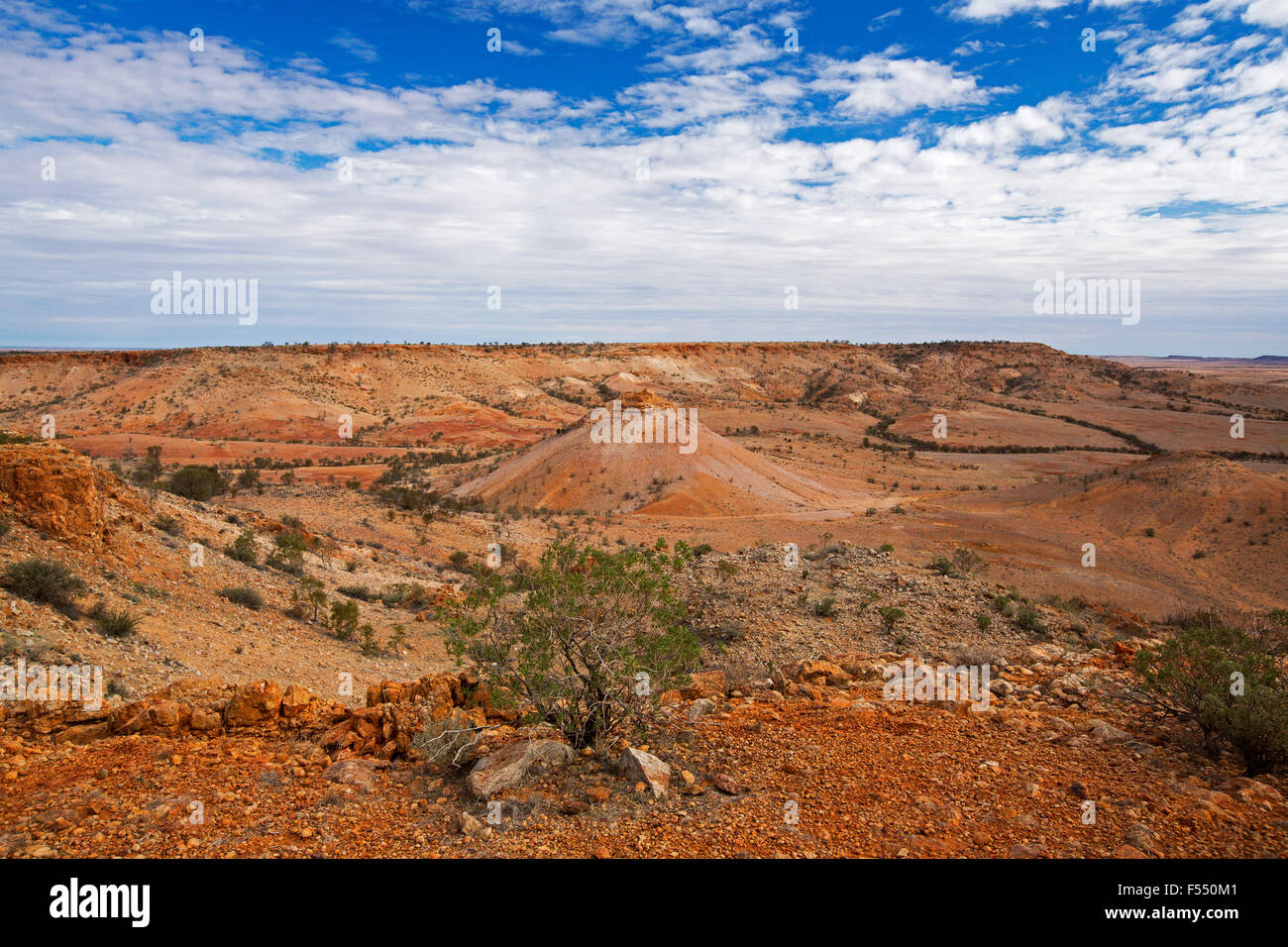 Australian Outback il paesaggio dalla collina lookout, vetta conica salendo dalla valle orlati con rocky red colline sterili, fiori selvatici, cielo blu Foto Stock