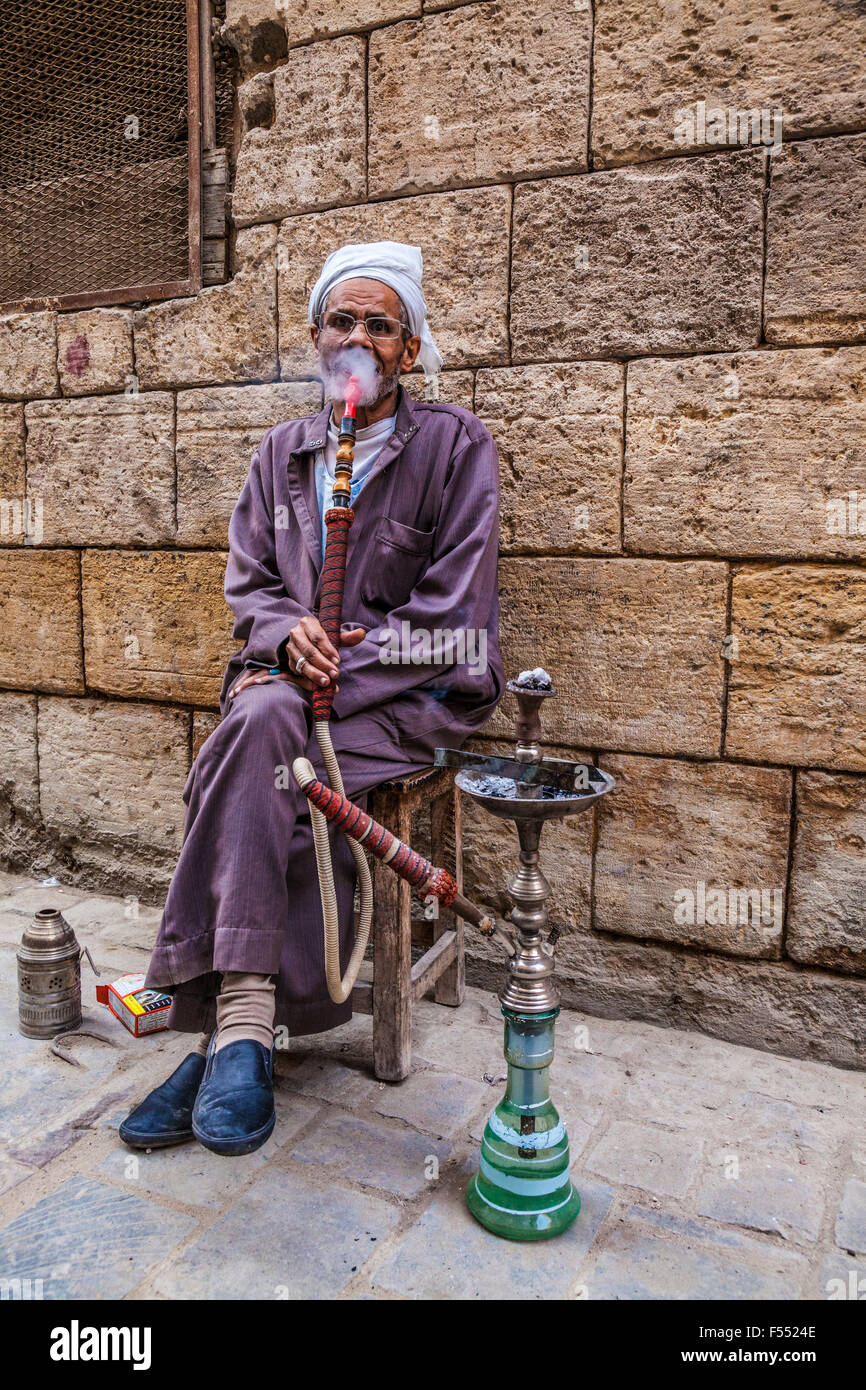 Uomo arabo fuma una tradizionale arabo shisha in Khan el-Khalili souk al Cairo. Foto Stock
