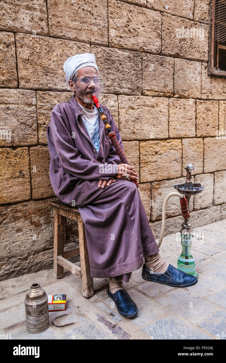 Uomo arabo fuma una tradizionale arabo shisha in Khan el-Khalili souk al Cairo. Foto Stock