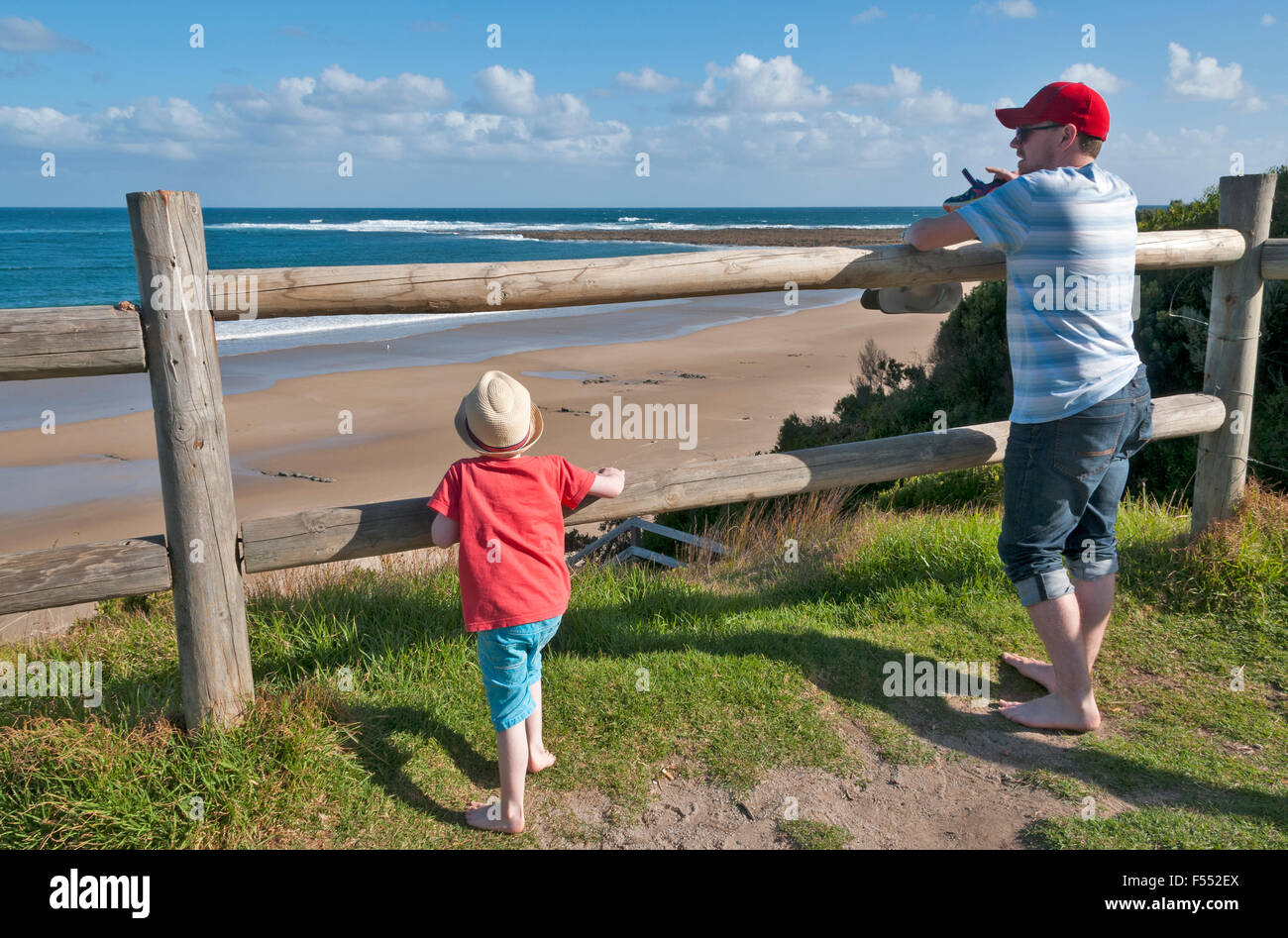 Padre e figlio che guarda al mare dalle rocce piatte sito fossile Inverloch Victoria Australia Foto Stock
