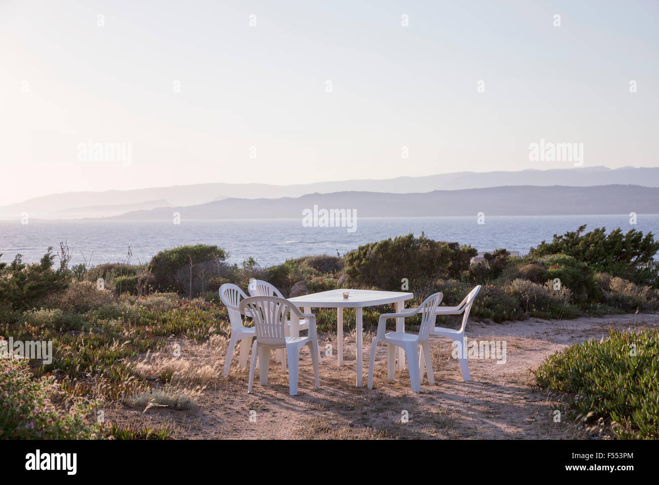 Tavolo e sedie e ombrellone sulla spiaggia contro il cielo chiaro Foto Stock