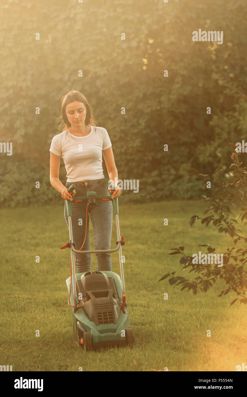 Donna di erba a fresare con tosaerba in cantiere Foto Stock