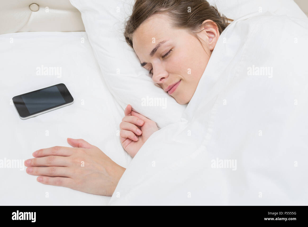 Angolo di alta vista della bella donna che dorme con smart phone sul cuscino a letto Foto Stock