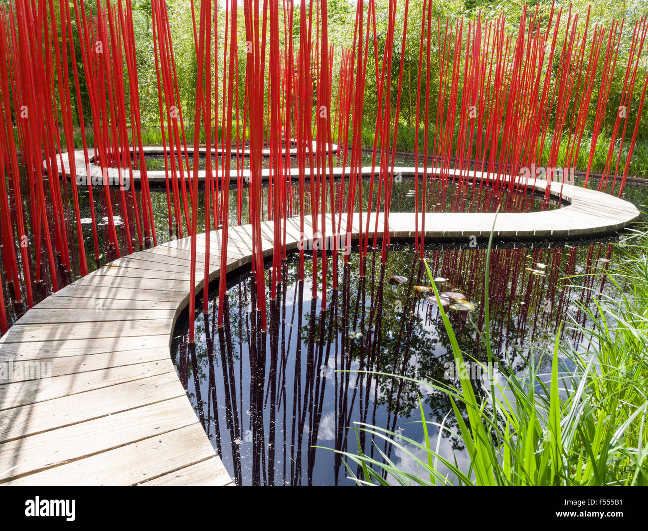 Il Carré et Rond da Kongjian Yu. Un incurvamento boardwalk attraverso un laghetto nero con rosso brillante poli a guidare il vostro modo attraverso la curva Foto Stock