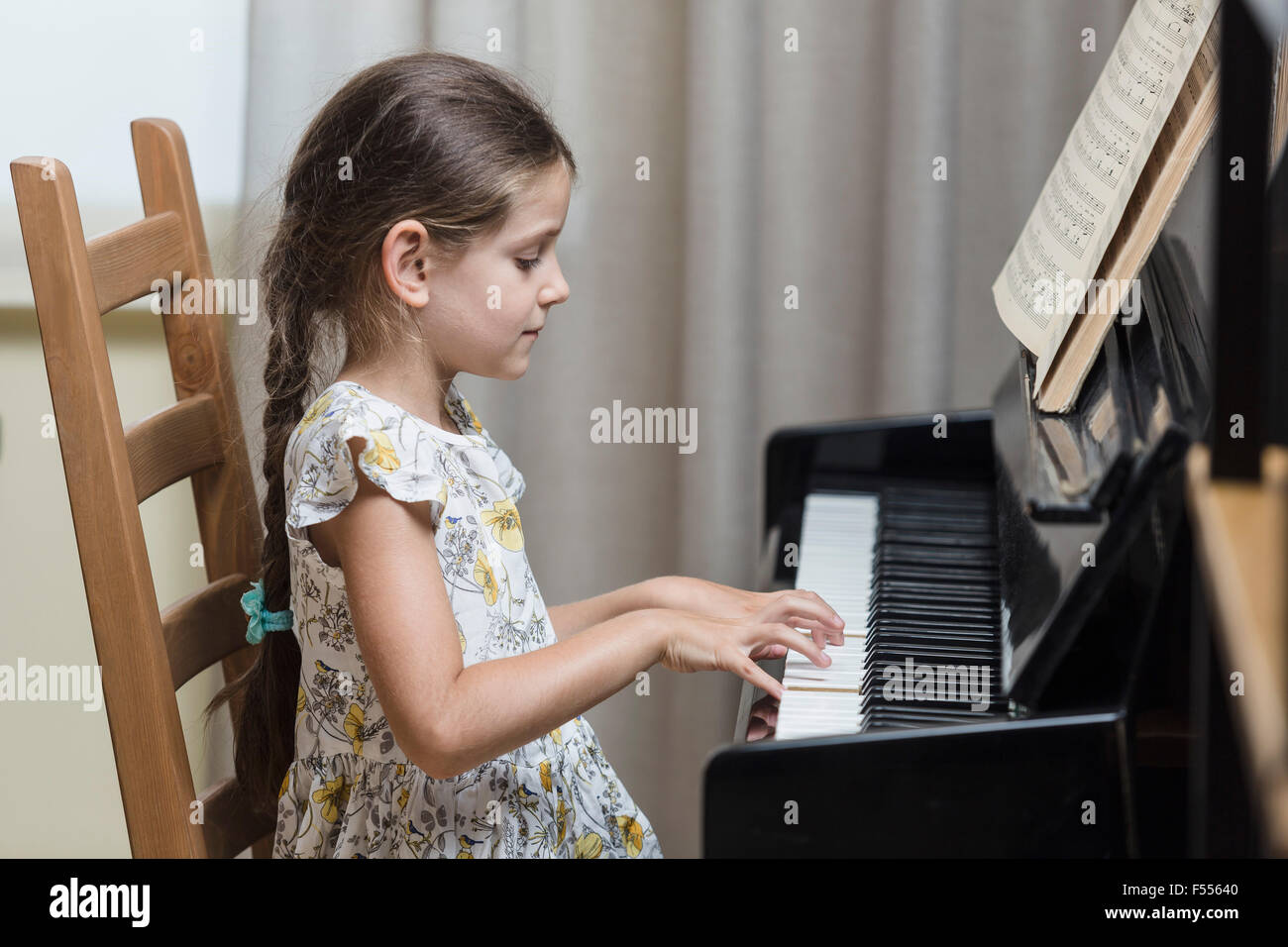 Vista laterale di una ragazza suonare il pianoforte a casa Foto Stock