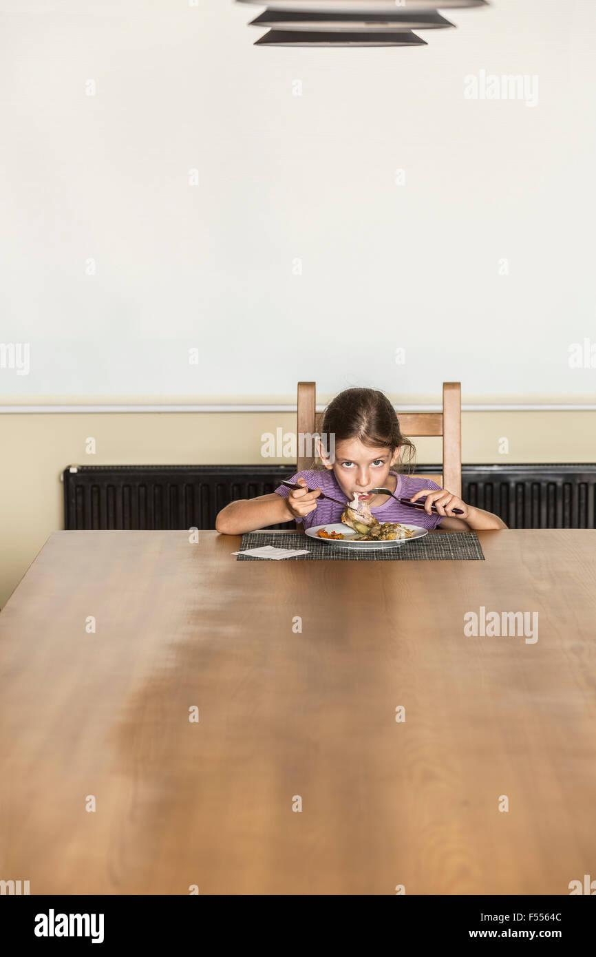 Ritratto di ragazza a mangiare cibo al tavolo da pranzo in casa Foto Stock