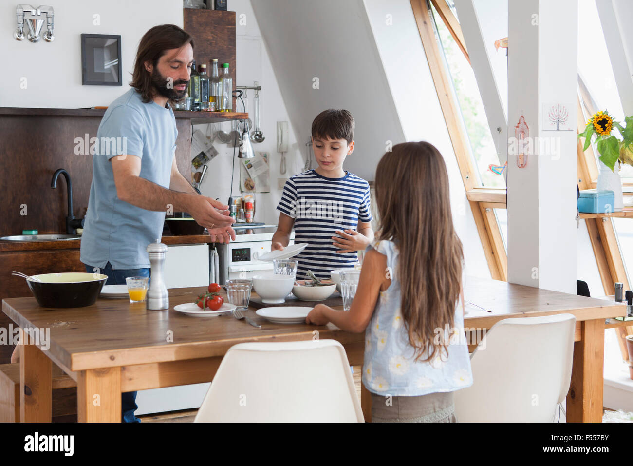Padre e figli nella tabella di impostazione per il pranzo in cucina Foto Stock