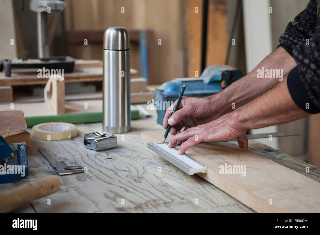 Immagine ritagliata del falegname maschio marcatura sul legno in officina Foto Stock
