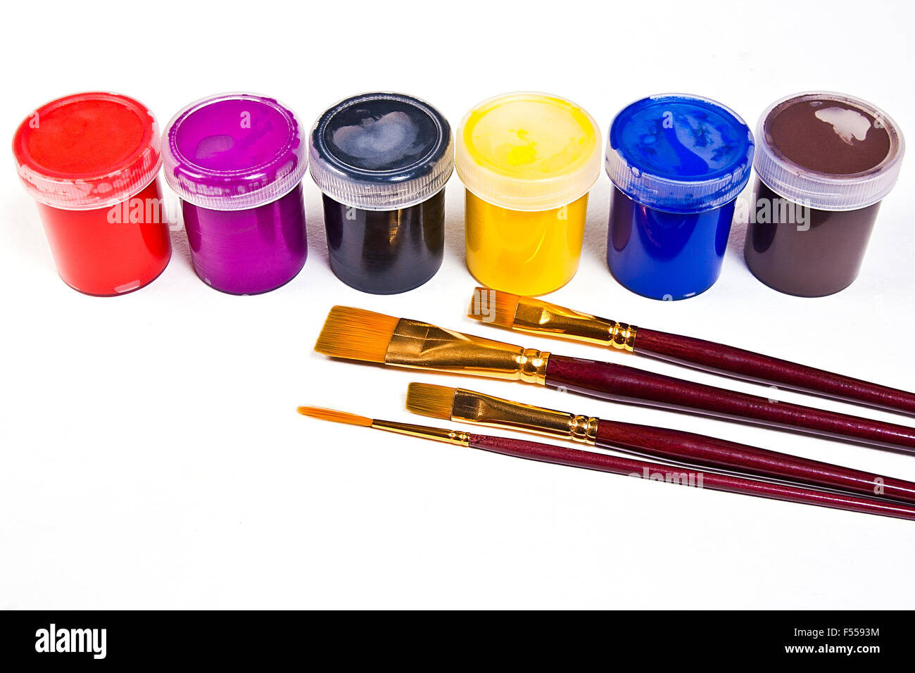 Bottiglie con gouache vernici e diversi tipi di spazzole per quadri artistici sullo sfondo bianco. Foto Stock