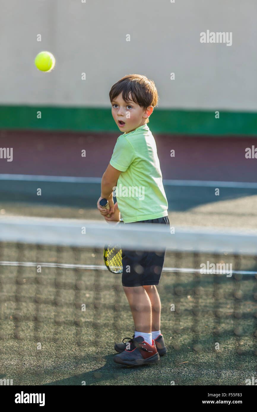 Ragazzo giocando a tennis sul campo in tribunale Foto Stock