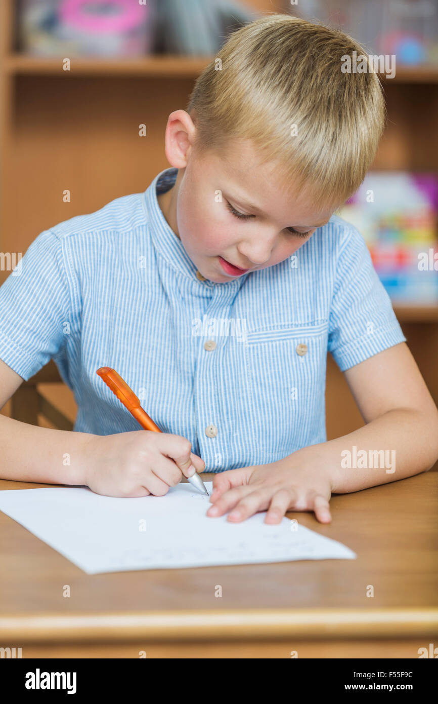 Close-up di boy scrittura su carta a tavola Foto Stock