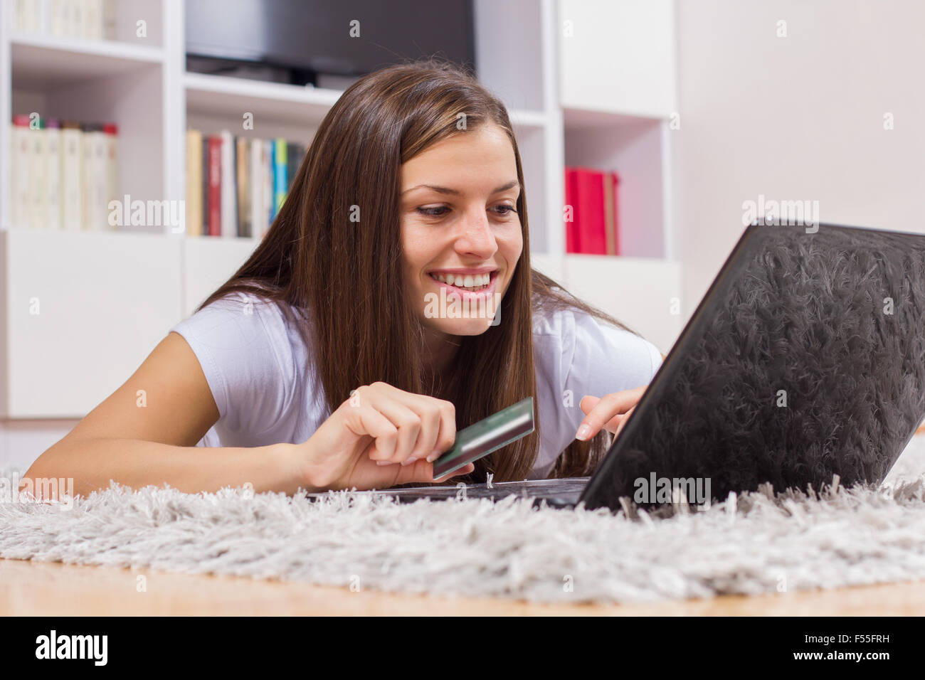 Lo shopping online. Bella e sorriso giovane donna con pagamenti tramite carta di credito su internet a casa. Foto Stock