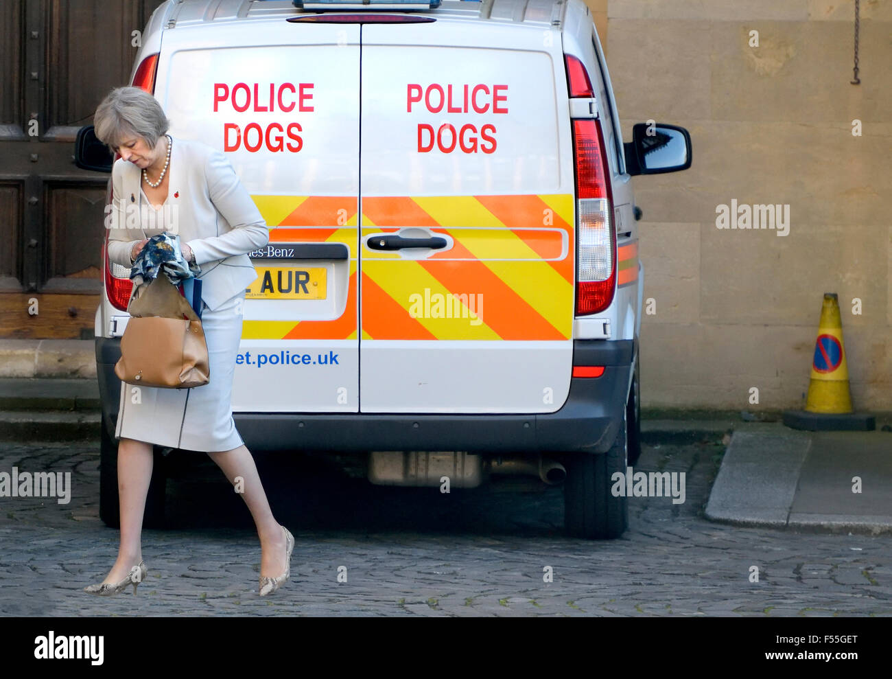 Theresa Maggio MP, Home Secretary, passeggiate passato un cane di polizia van nei giardini delle case del Parlamento, Westminster, London Foto Stock