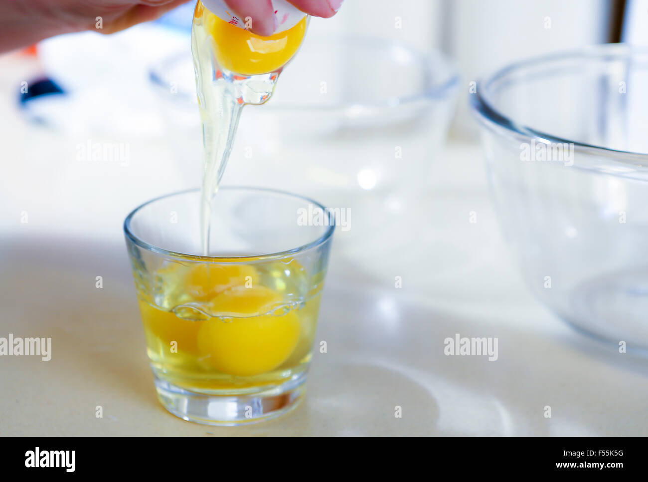 La rottura di un uovo in un bicchiere Foto Stock