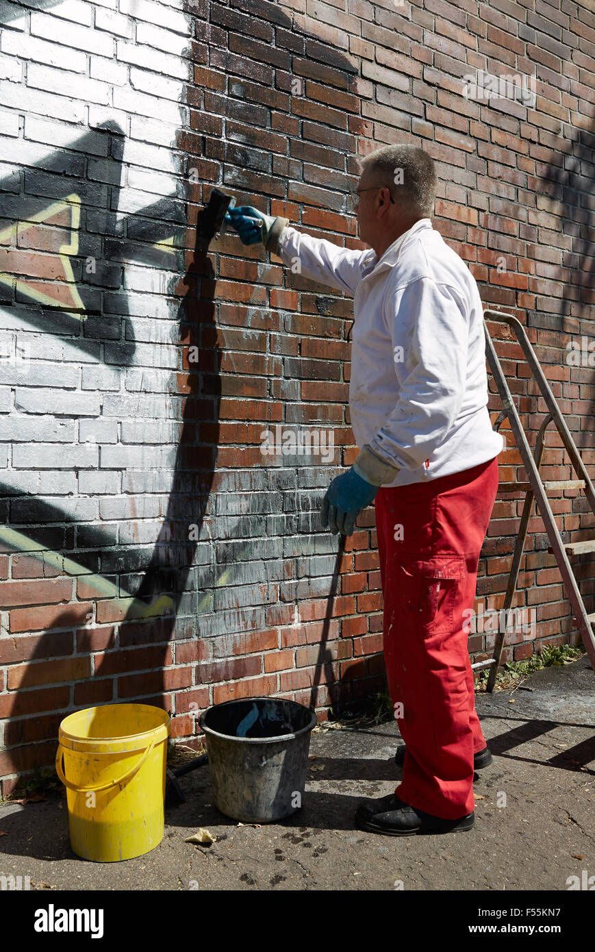 11.06.2015, Berlin, Berlin, Germania - rimozione dei graffiti su un muro di mattoni da un artigiano di una ditta specializzata. Con un pennello, un liquido viene applicato per staccare la vernice spray e quelli lavati in porto. 00R150611D015CAROEX.JPG - non per la vendita in G E R M A N Y, A U S T R I A, S W I T Z e R L A N D [modello di rilascio: NO, la proprietà di rilascio: NO (c) caro agenzia fotografica / Ruffer, http://www.caro-images.pl, info@carofoto.pl - nel caso di utilizzo di foto per non-scopi giornalistici, siete pregati di contattare l'Agenzia - la foto è soggetto a royalty!] Foto Stock