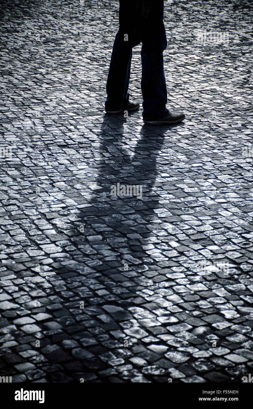 Misterioso uomo a camminare su una strada acciottolata Foto Stock