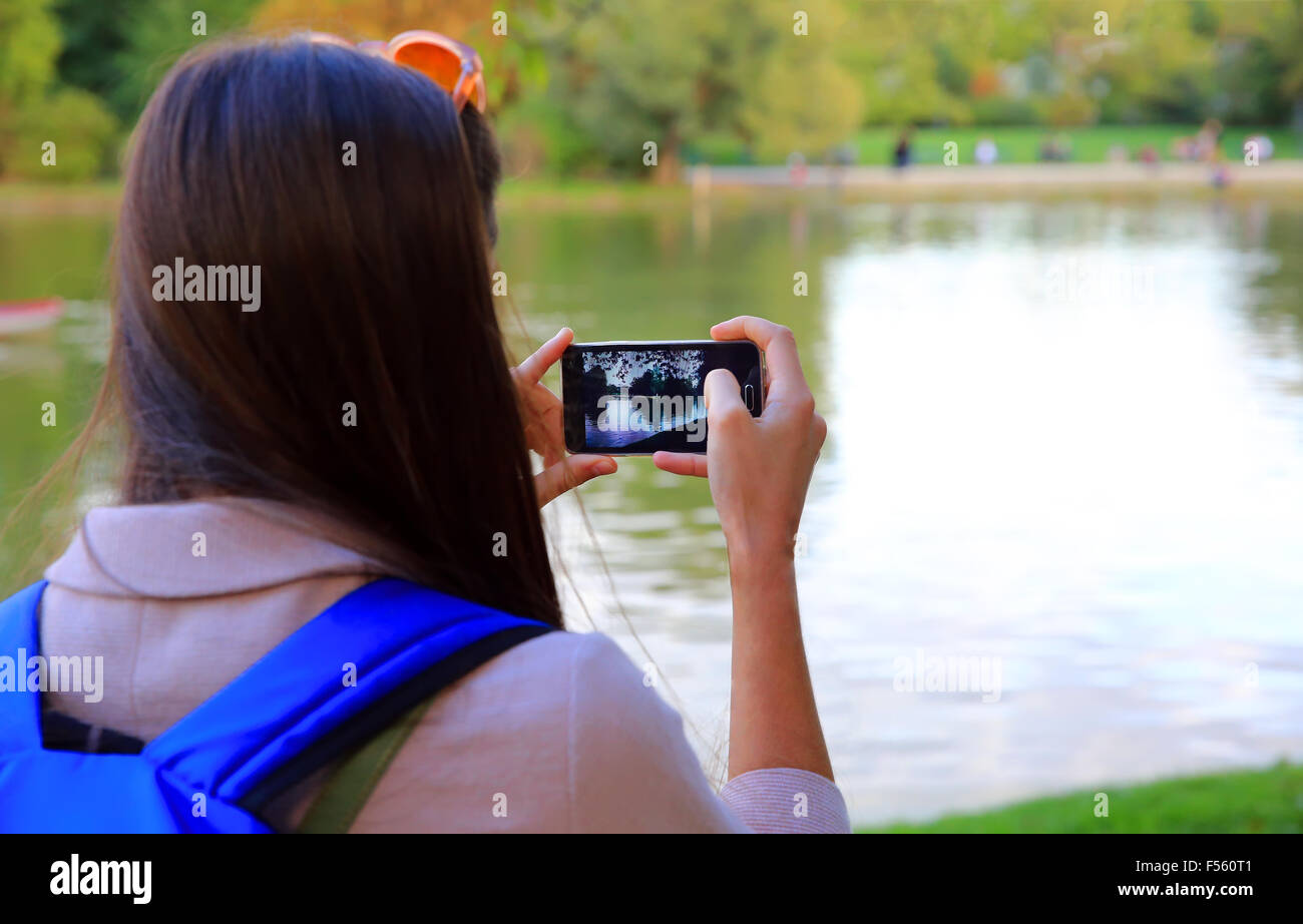 Giovane donna fotografare sul telefono cellulare in posizione di parcheggio Foto Stock