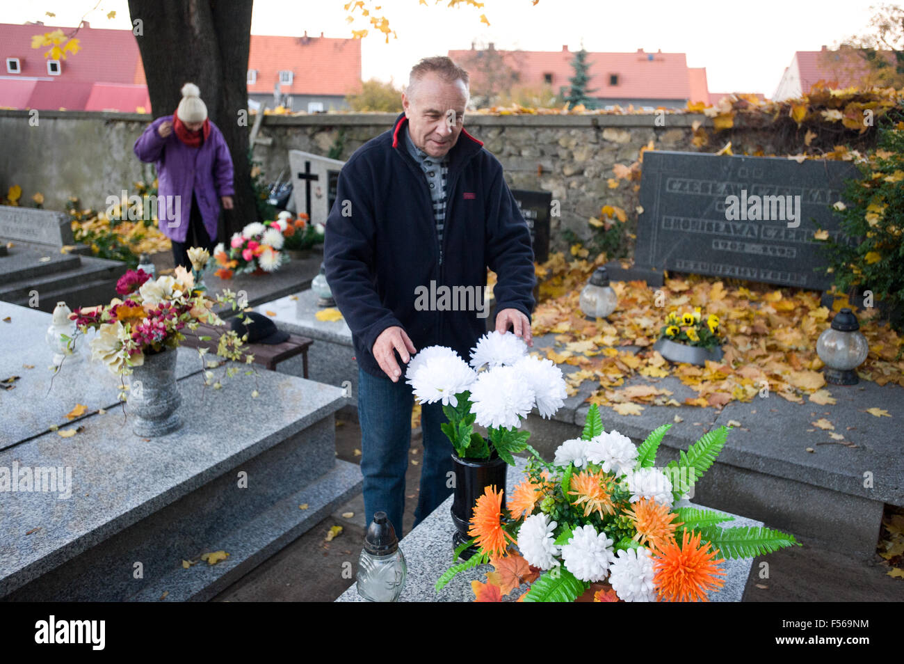 Wielun, Polonia. 28 ottobre, 2015. L uomo rende omaggio floreale sulla tomba come una parte di preparati per celebrare catholic il giorno di Tutti i Santi il 1 novembre. Foto Stock