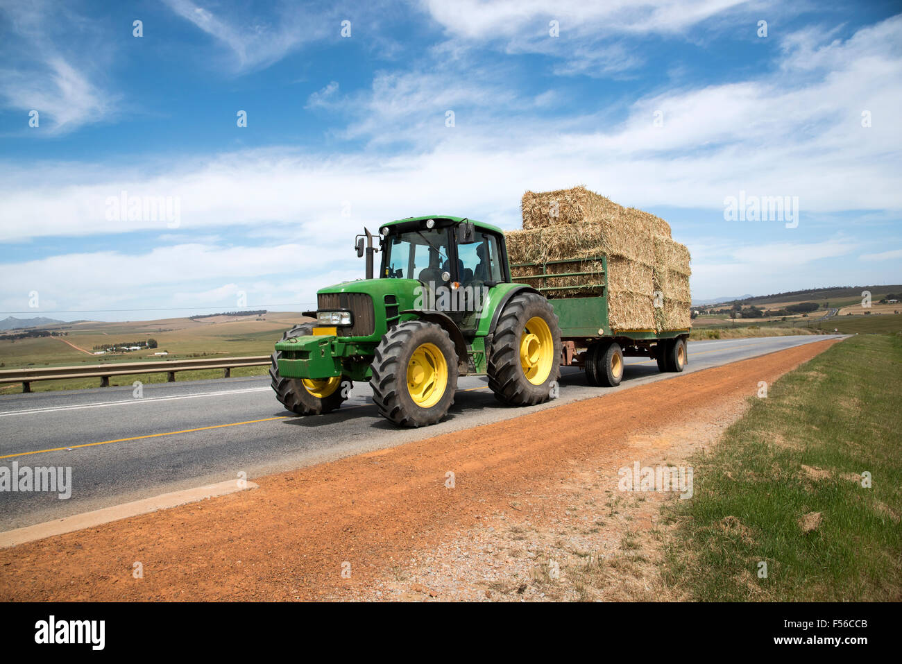 Azienda agricola il trattore e il rimorchio trainato un carico di paglia su una strada pubblica in Swartland regione del Sud Africa Foto Stock