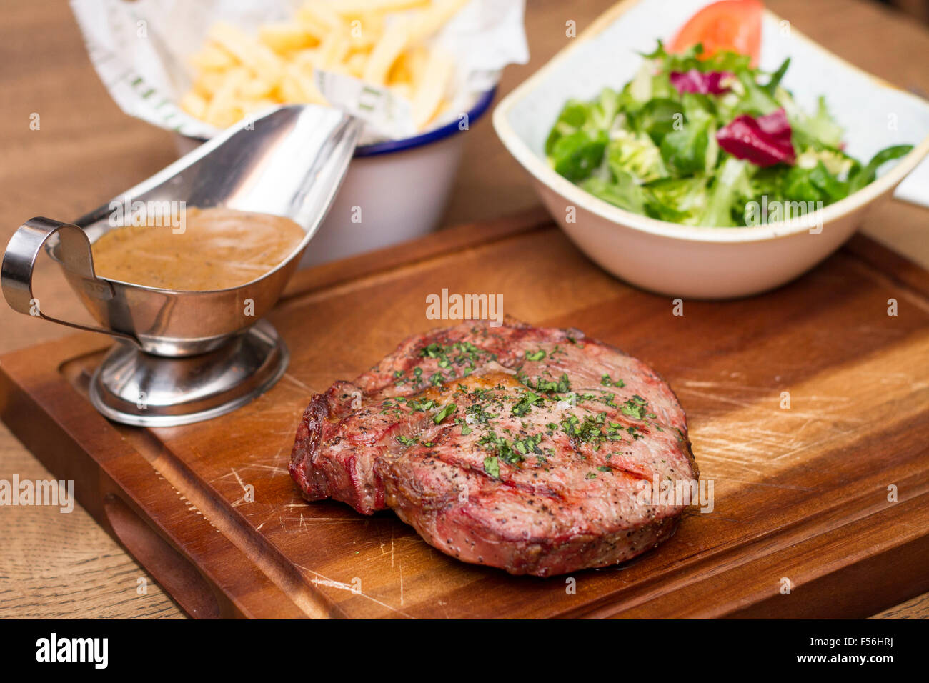 La carne di manzo britannica di filetto con una ciotola di insalata e patatine su una tavola di legno Foto Stock