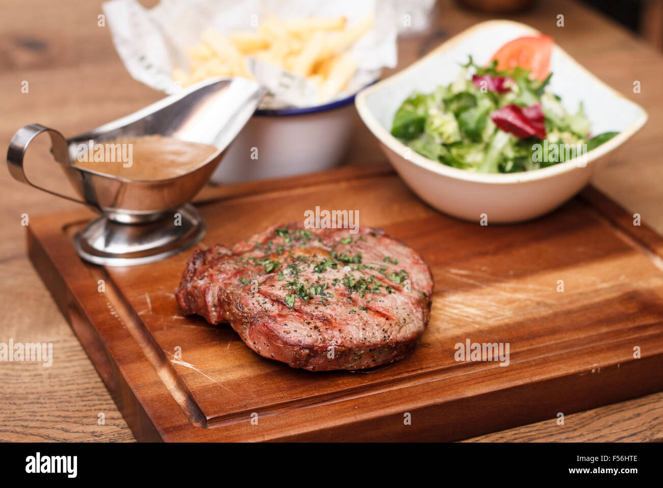 La carne di manzo britannica di filetto con una ciotola di insalata e patatine su una tavola di legno Foto Stock