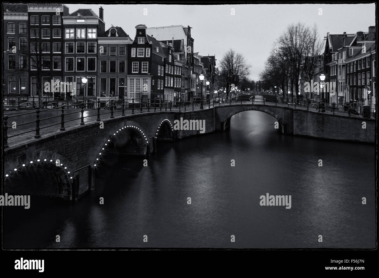 Immagine in bianco e nero con i famosi ponti e canali di Amsterdam dopo il tramonto, una lunga esposizione l'immagine orizzontale. Foto Stock