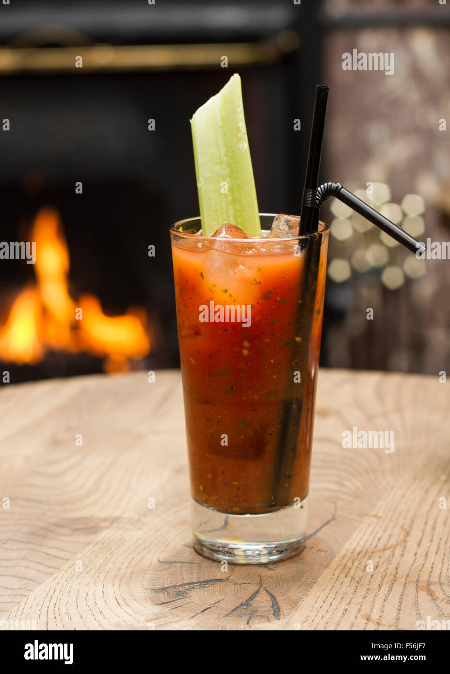 Bloody Mary cocktail con una costa di sedano davanti a un caminetto Foto Stock