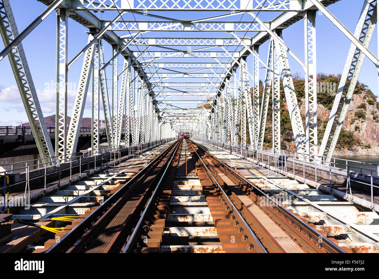 Giappone, Inuyama. Kiso Linea ferroviaria privata. Casella di trave in acciaio ponte ferroviario, vista lungo la parte interna del ponte, diurno, sole, cielo blu. Foto Stock