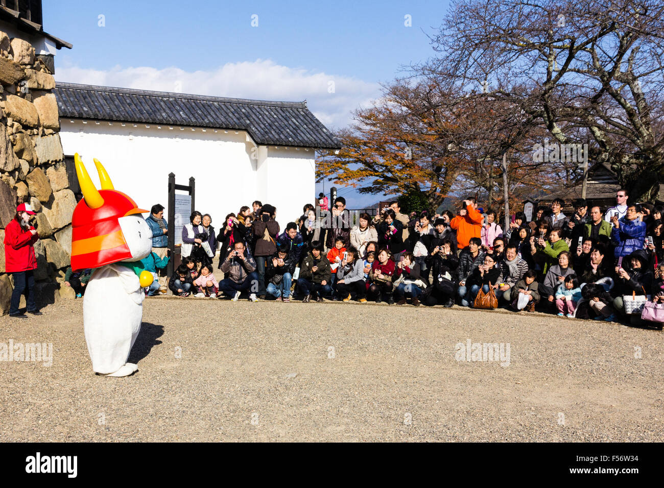 Il castello di Hikone e mascotte della città, gatto bianco, rosso da indossare casco samurai e la campana attorno al collo. Noto come Hikonyan. Vista laterale, in piedi rivolta verso il pubblico. Foto Stock