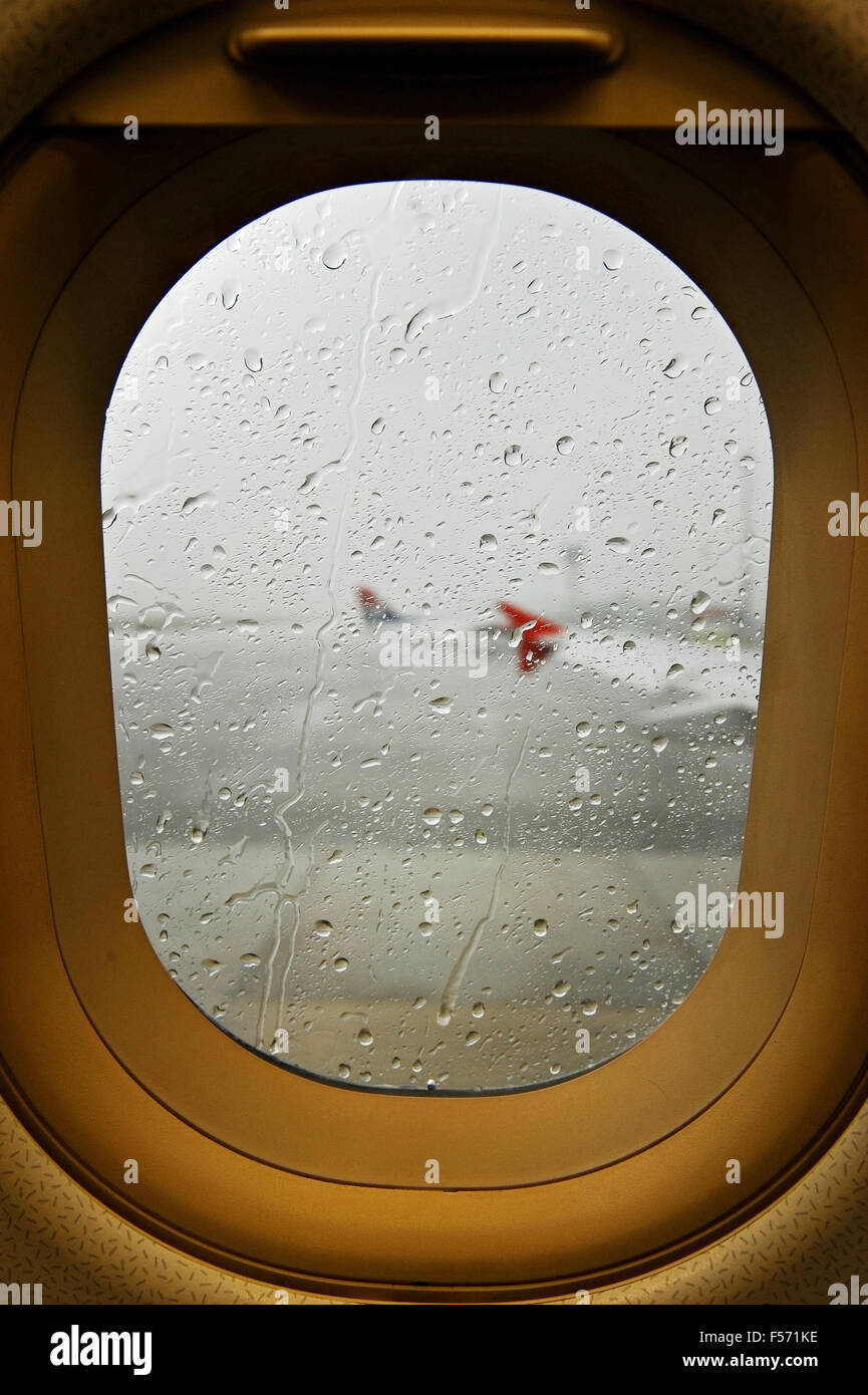 Le gocce di pioggia sono visti al di fuori di un aereo oblò durante un temporale in un aeroporto Foto Stock