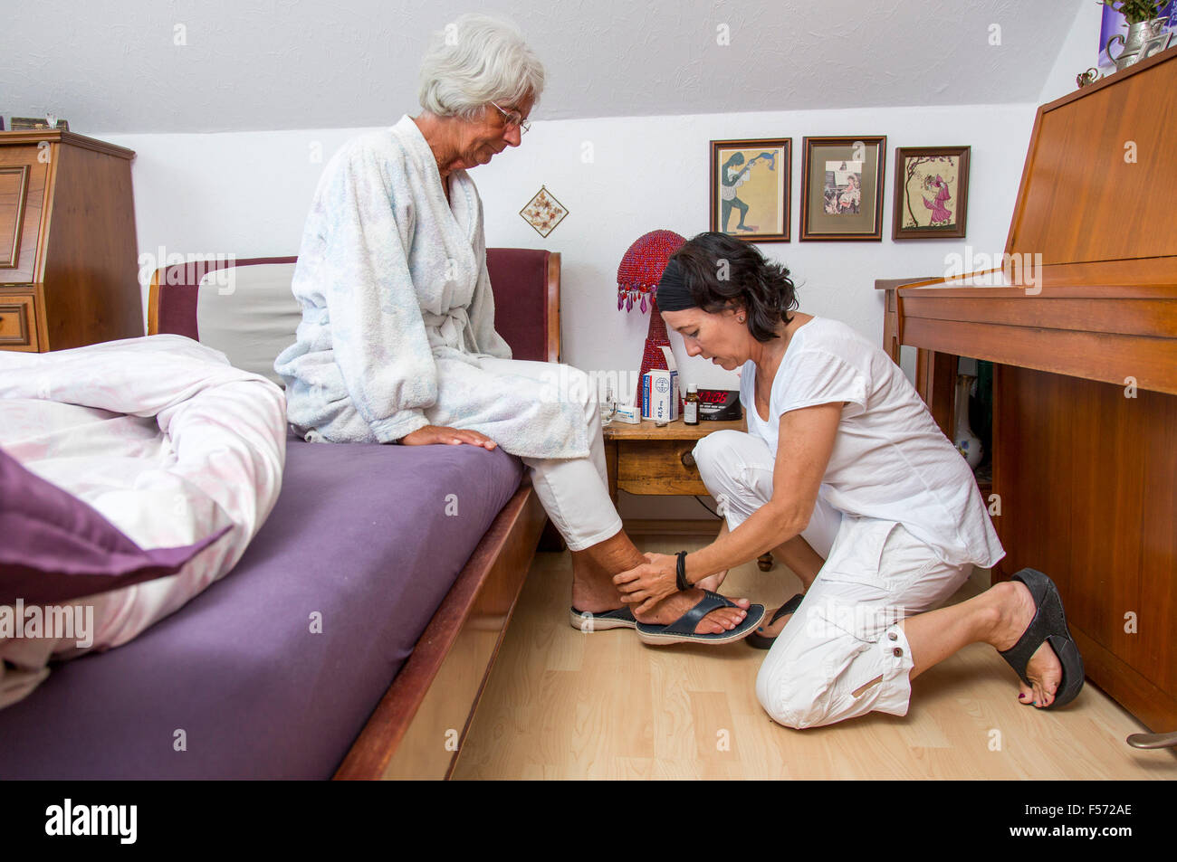Assistenza agli anziani a casa, infermiere di cure per una donna anziana, scendere dal letto, Foto Stock