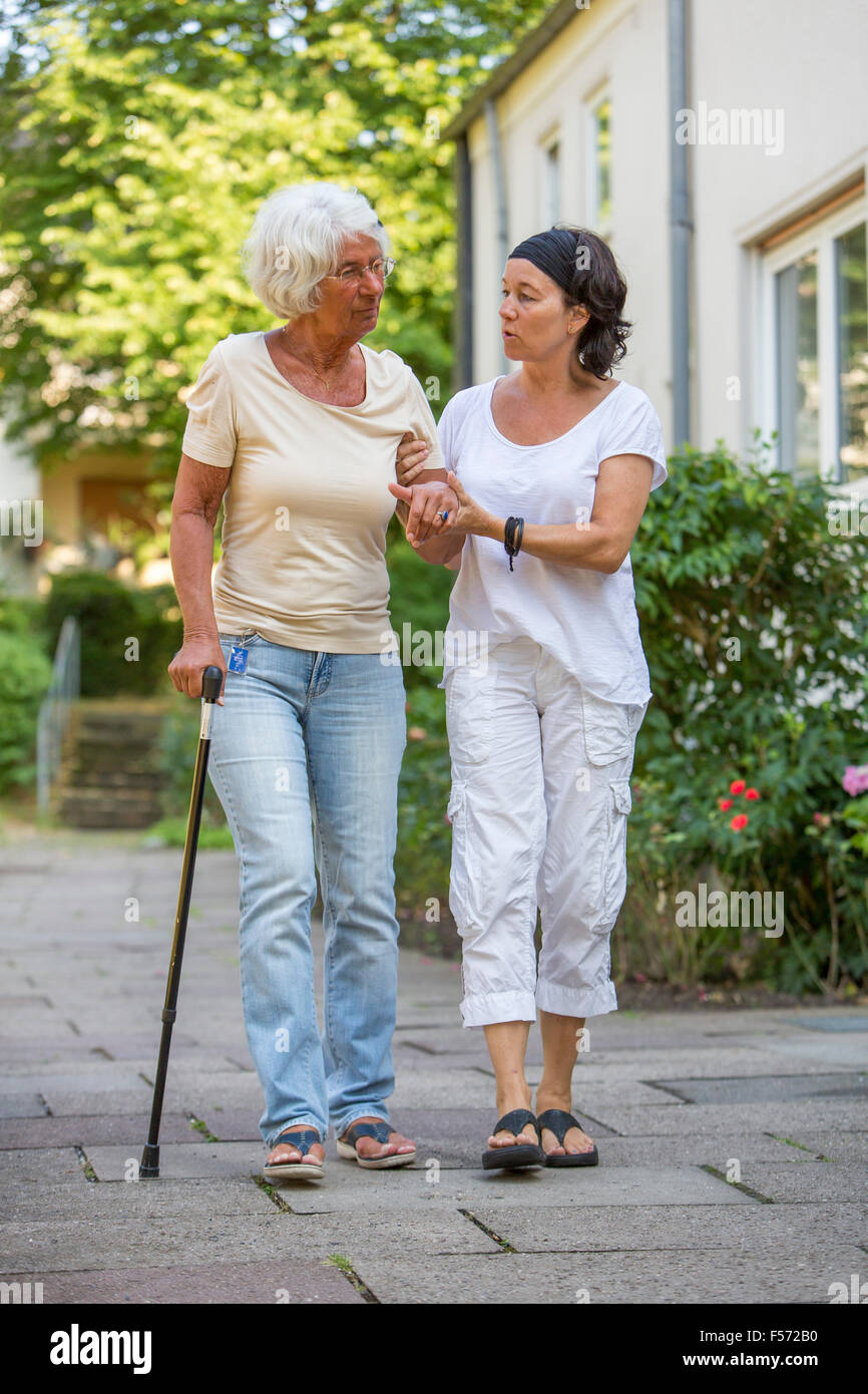 Assistenza agli anziani a casa, infermiere di cure per una donna anziana, passeggiate a piedi l'aids, Foto Stock