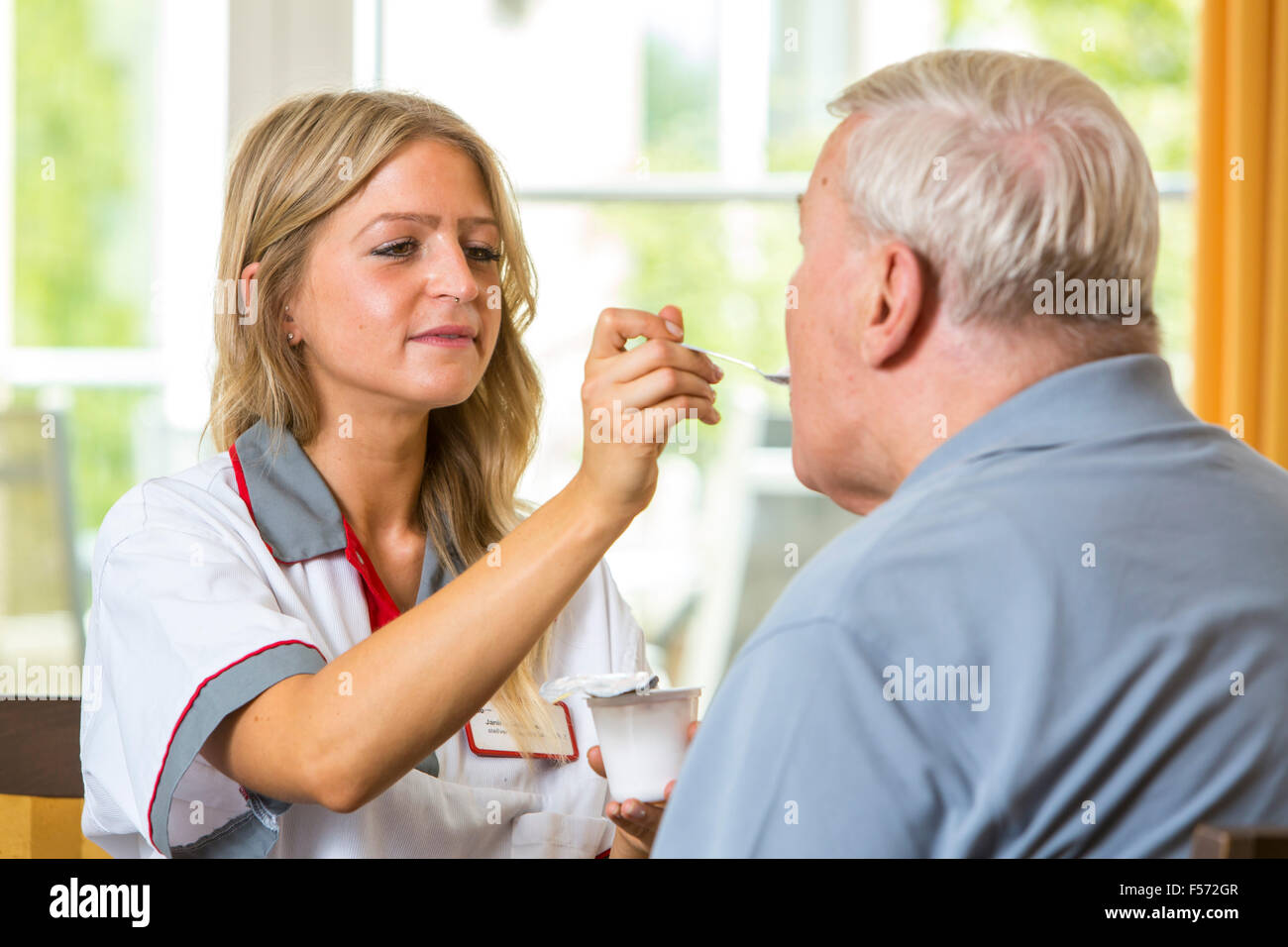Assistenza agli anziani in una casa di cura, infermiere aiuta un anziano uomo mangiare il suo pasto, alimentazione cibo, Foto Stock