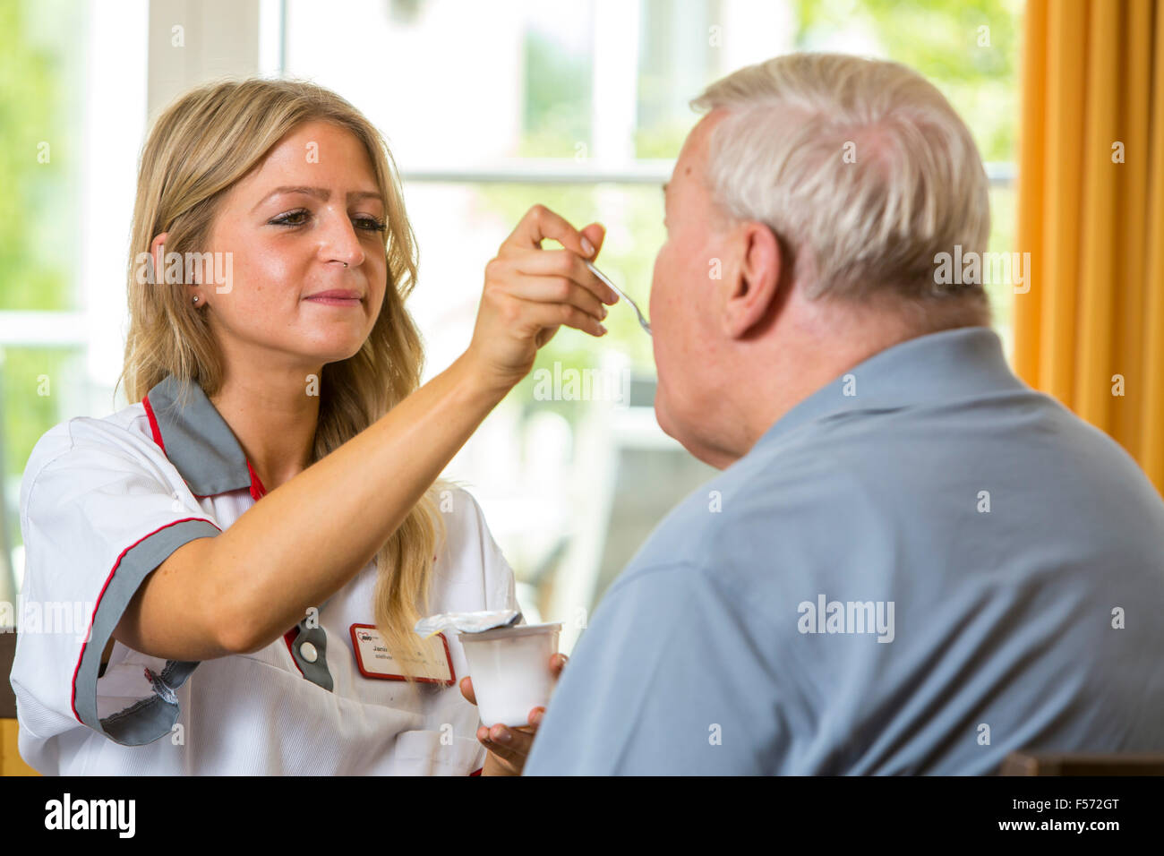 Assistenza agli anziani in una casa di cura, infermiere aiuta un anziano uomo mangiare il suo pasto, alimentazione cibo, Foto Stock