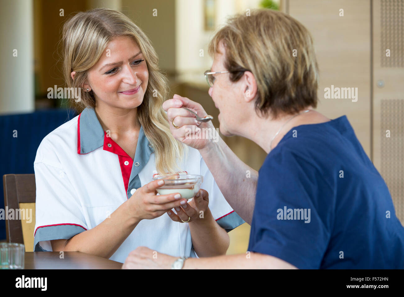 Assistenza agli anziani in una casa di cura, infermiere aiuta una donna anziana a mangiare il suo pasto, cibo, alimentazione Foto Stock