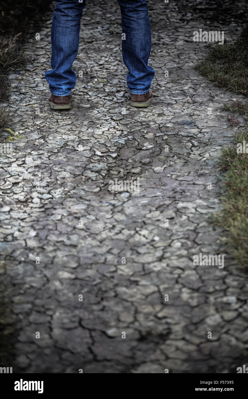 L uomo per le gambe in piedi sul suolo incrinato Foto Stock