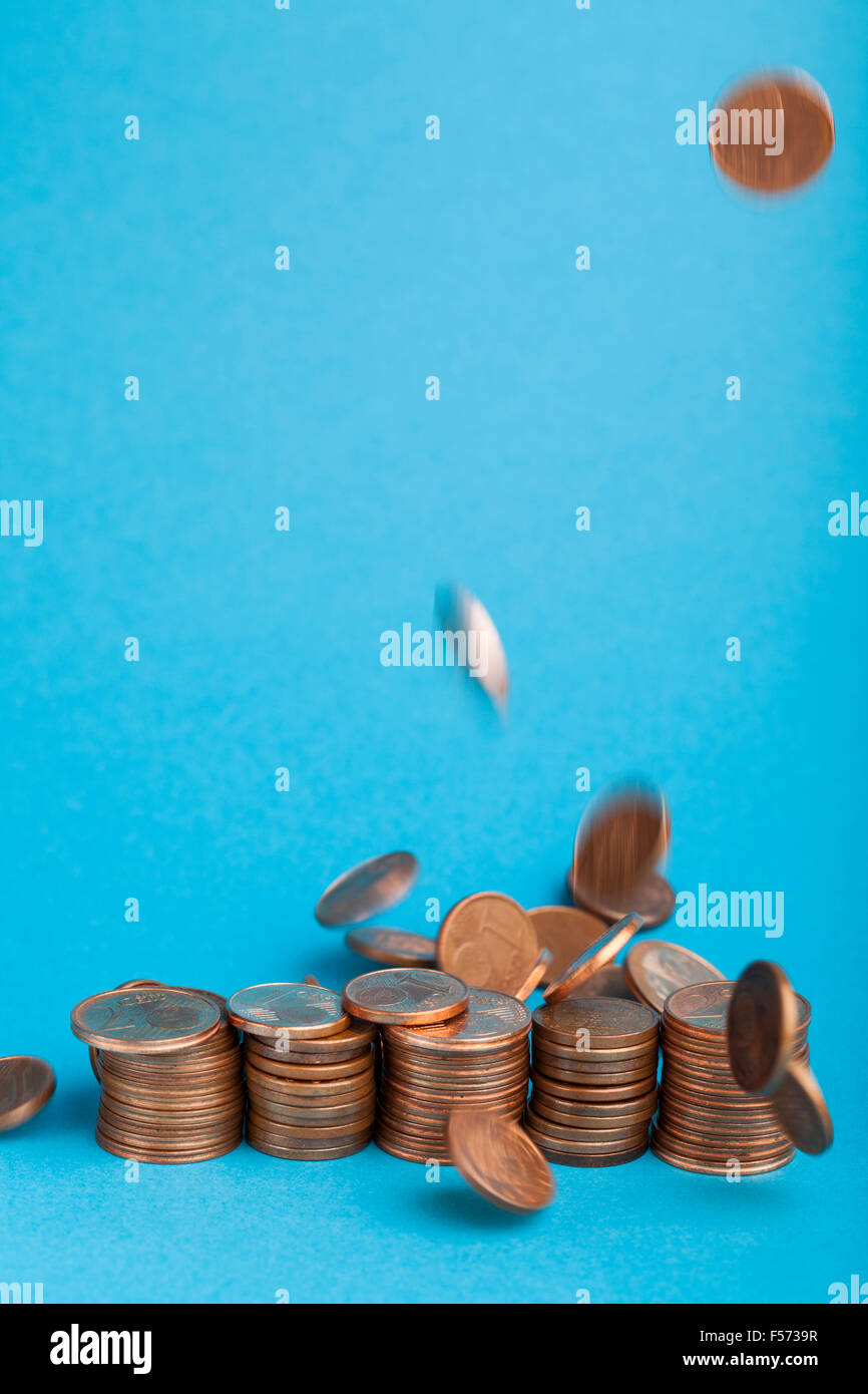 La caduta di cent di Euro monete in un centesimo e due centesimi a tagli su sfondo blu. Foto Stock