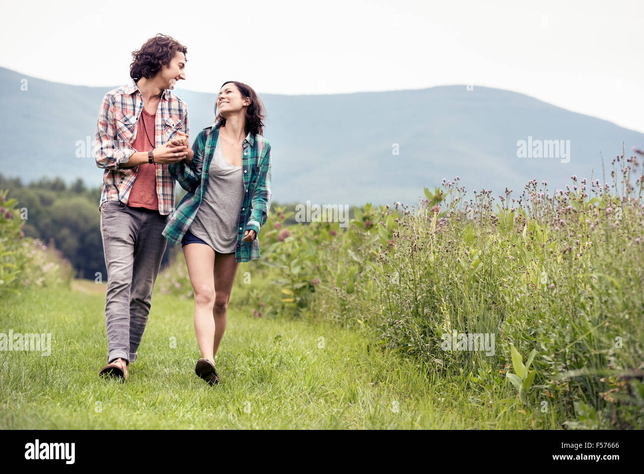 Un giovane uomo e donna a piedi attraverso un prato in campagna. Foto Stock