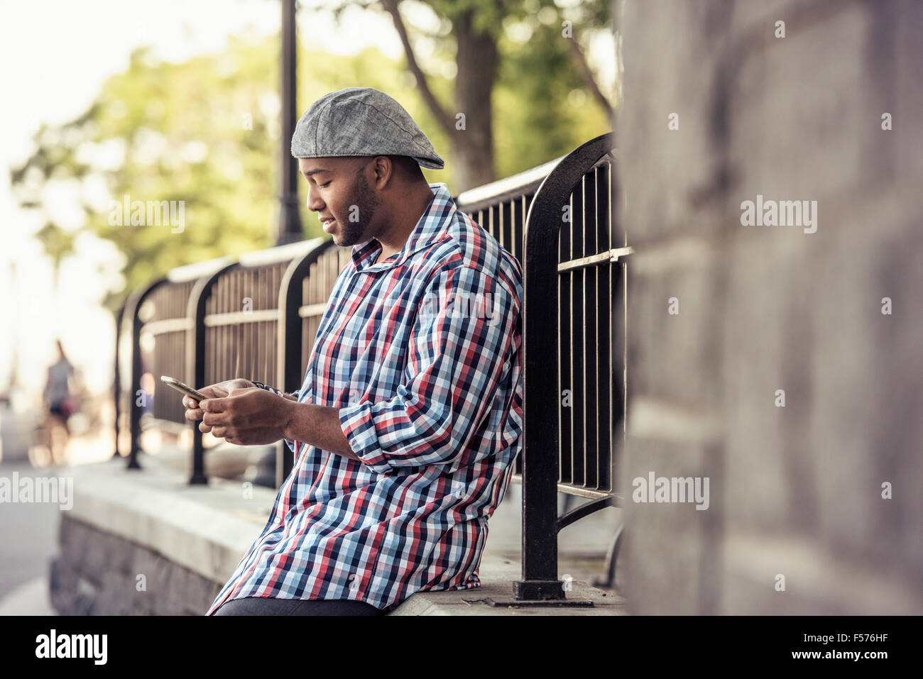 Un uomo appoggiato su di una ringhiera, guardando uno smart phone Foto Stock