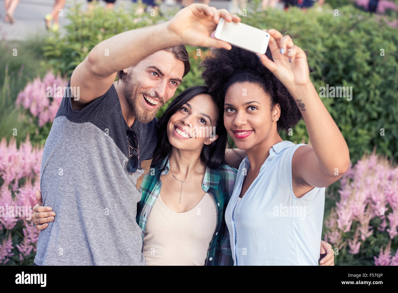 Due donne e un uomo che posano per una selfie Foto Stock