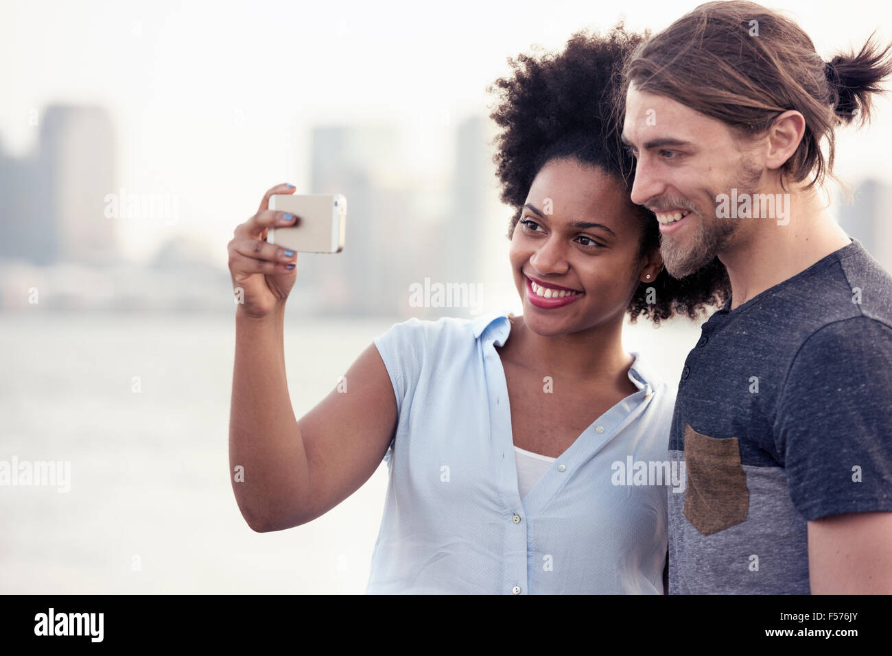 Un giovane uomo e donna prendendo un selfie sul lungomare in una città Foto Stock
