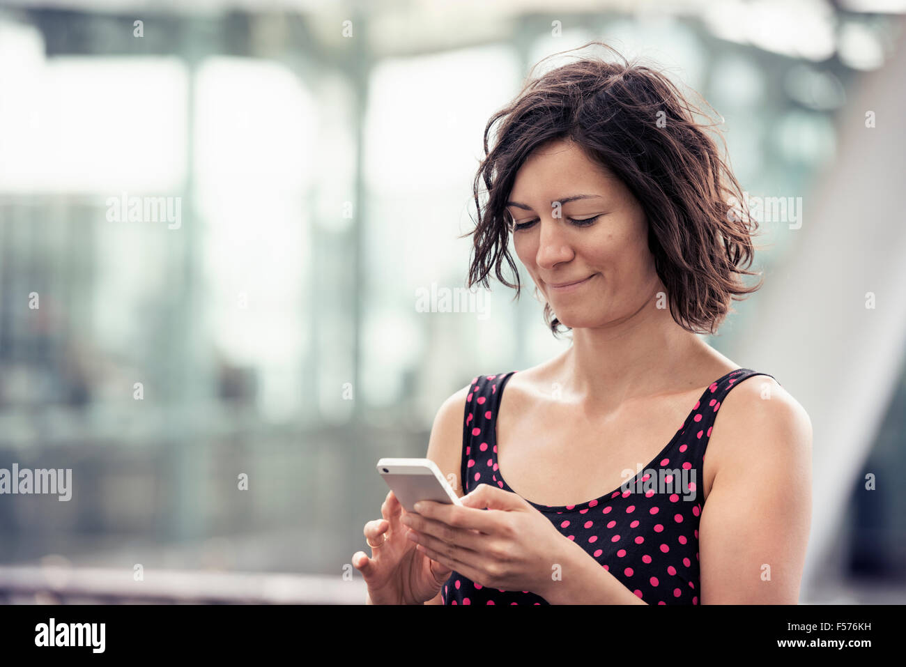 Una donna su una strada con il suo telefono cellulare, controllo dei messaggi Foto Stock