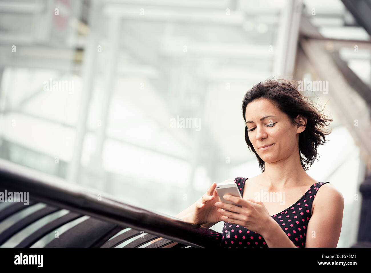 Una donna in piedi al di fuori di un edificio controllando il suo telefono cellulare. Foto Stock