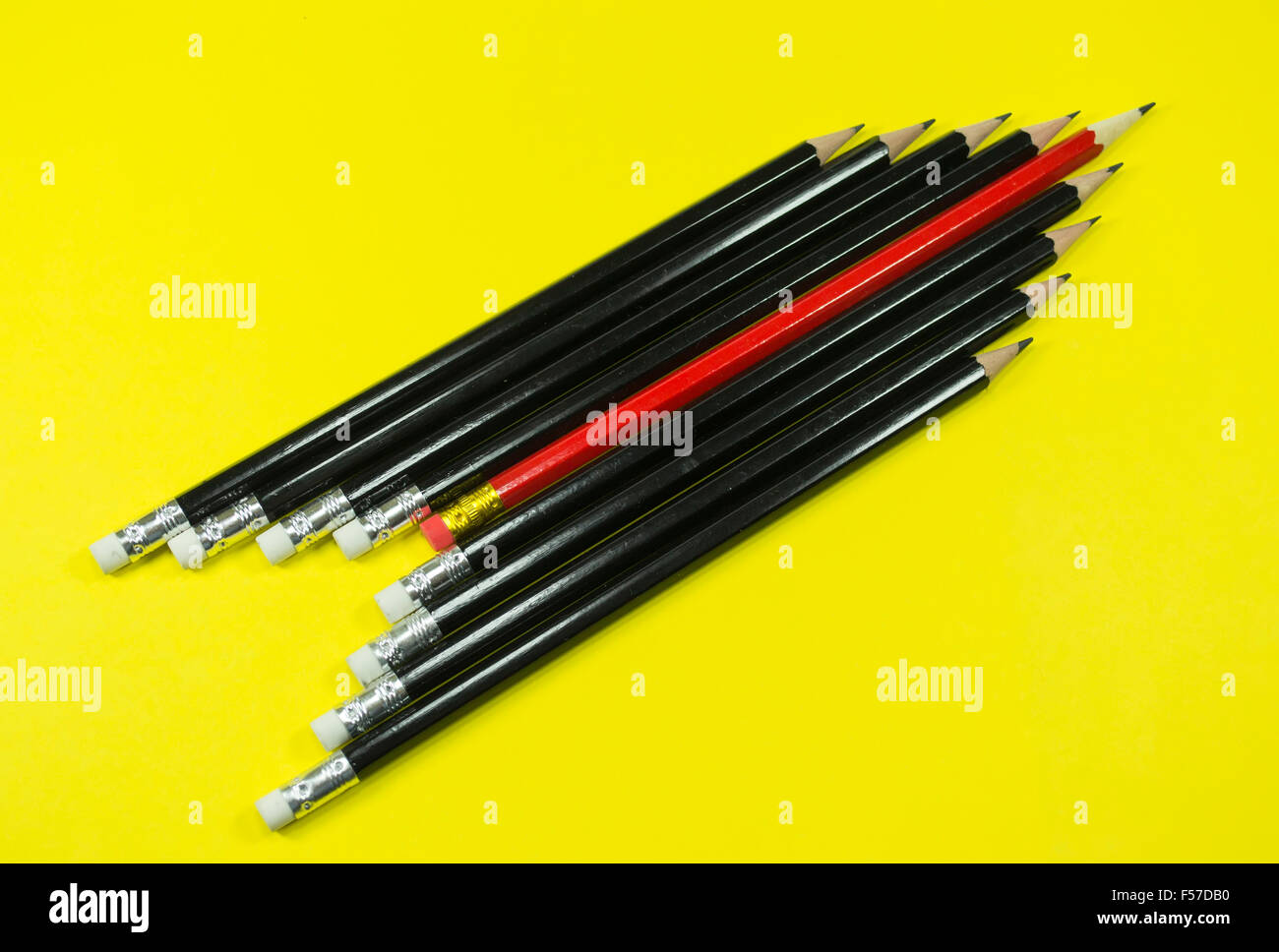 Legno nero matite impostato con uno rosso nel mezzo a forma di freccia o razzo su sfondo giallo Foto Stock