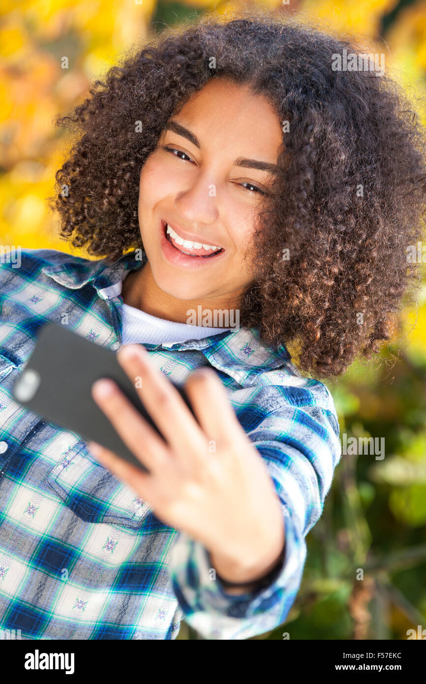 Bella felice razza mista americano africano ragazza adolescente femmina sorridente bambino tenendo selfie fotografare con il telefono cellulare Foto Stock
