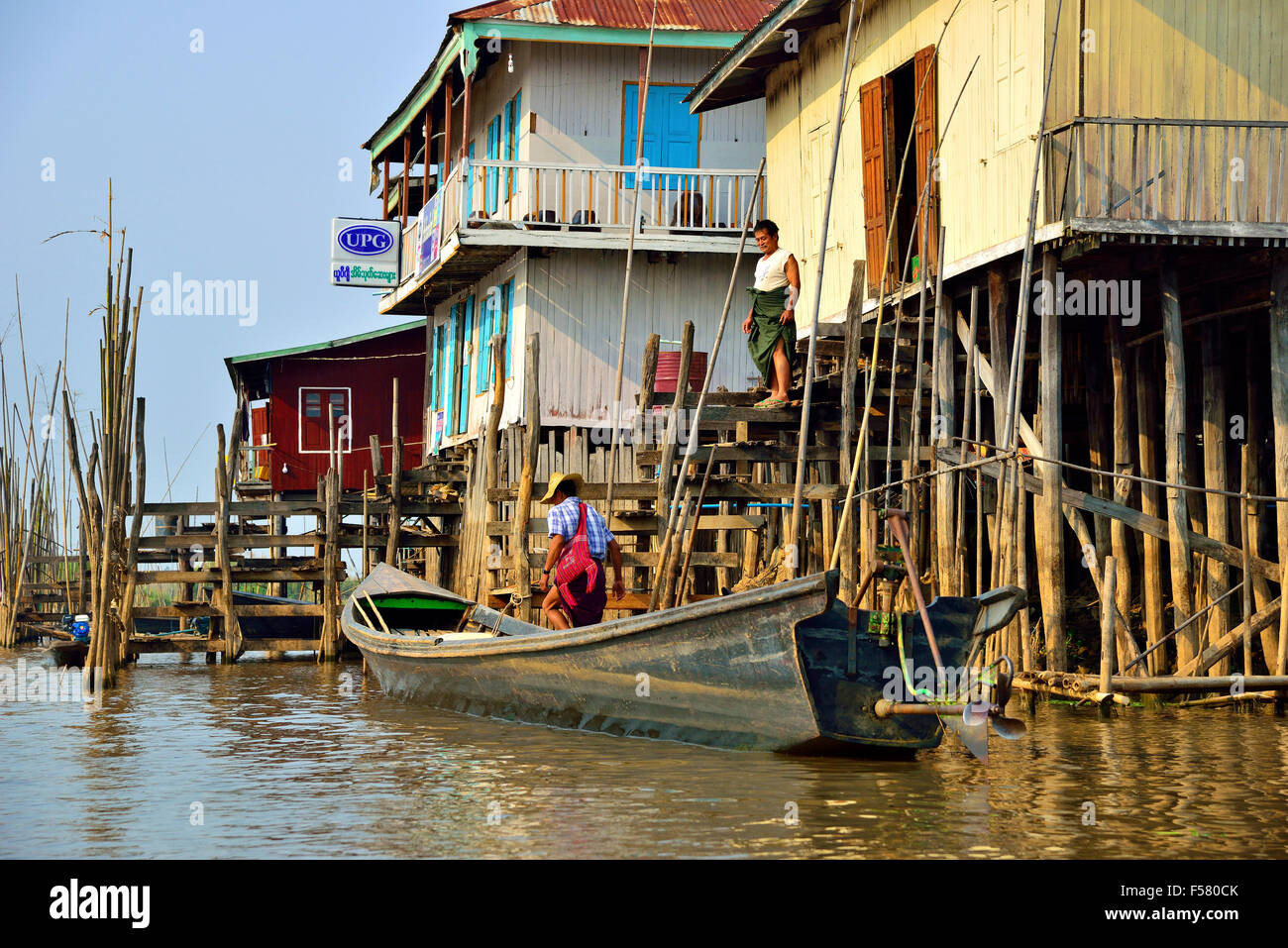 Minoranza etnica Intha persone che entrano in una barca a coda lunga fuori dalla loro casa palafitte sul lago Inle, Stato Shan, Myanmar, ex Birmania Foto Stock